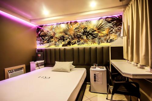 a room with a bed and a desk with purple lights at Adrenalina Motel Itaquera - Arena Corinthians in Sao Paulo