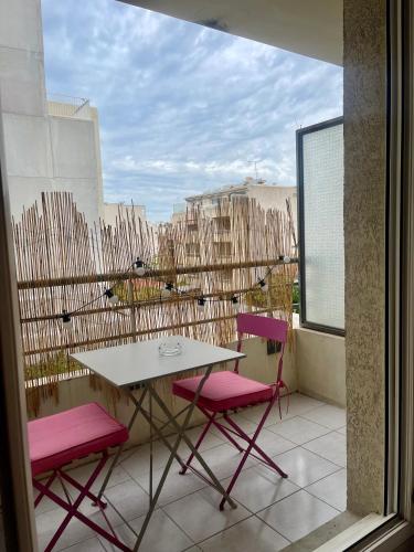 - un balcon avec une table et deux chaises roses dans l'établissement Studio avec place de parking à la timone, à Marseille