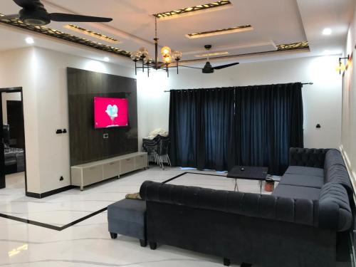 Luxurious kashmir house near Islamabad airport في Dhok Sandemār: غرفة معيشة مع أريكة وتلفزيون بشاشة مسطحة