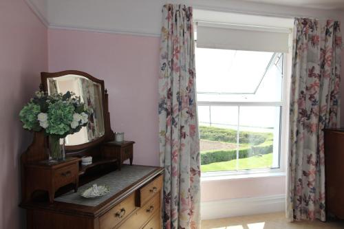 a room with a window and a dresser with a mirror at Spacious seaside family house in Aberdaron with large garden and stunning sea views in Aberdaron