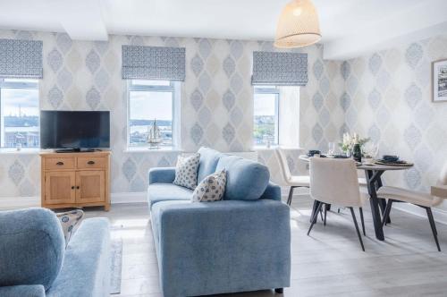 a living room with a blue couch and a table at Harbour View - 2 Bedroom Apartment - Milford Haven in Milford Haven