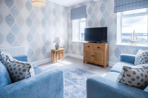 a living room with two blue chairs and a television at Harbour View - 2 Bedroom Apartment - Milford Haven in Milford Haven