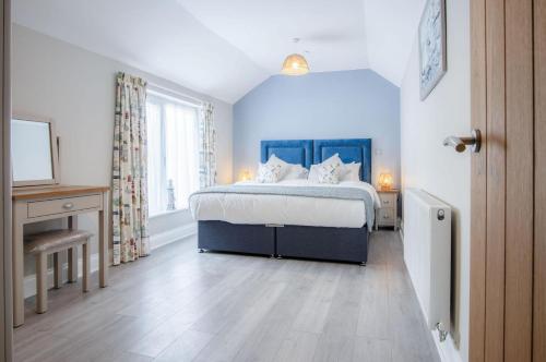 a bedroom with a bed with a blue headboard at Harbour View - 2 Bedroom Apartment - Milford Haven in Milford Haven