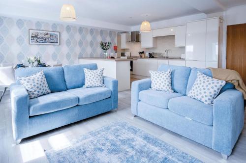 a living room with two blue couches and a kitchen at Harbour View - 2 Bedroom Apartment - Milford Haven in Milford Haven