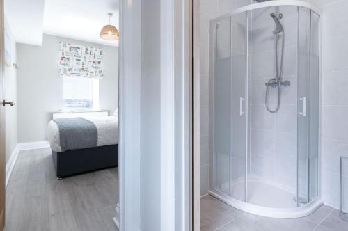 a bathroom with a glass shower with a bed at Harbour View - 2 Bedroom Apartment - Milford Haven in Milford Haven