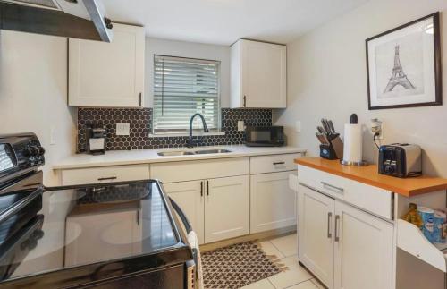 a kitchen with white cabinets and a sink at Cozy Heights 2 BD Bungalow, Walkable in Houston