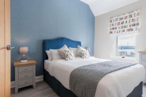 a bedroom with a large bed with a blue wall at Harbour Heights - 2 Bed Apartment - Milford Haven in Milford Haven
