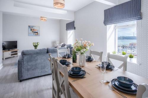 a dining room with a table with chairs and a couch at Beach Haven Hideout - 2 Bedroom - Milford Haven in Milford Haven
