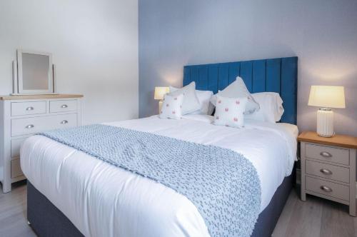 a bedroom with a large bed with a blue headboard and pillows at Beach Haven Hideout - 2 Bedroom - Milford Haven in Milford Haven