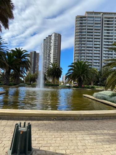 une fontaine dans un étang dans une ville avec de grands bâtiments dans l'établissement Gran Vista al Mar Moderno Depto Costa Montemar, à Concón