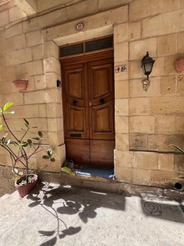 eine Holztür in einem Backsteingebäude mit Topfpflanze in der Unterkunft Three Apartment in Vittoriosa
