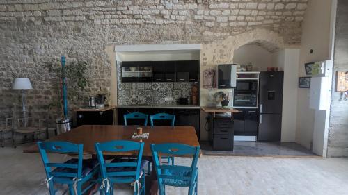 une cuisine avec une table en bois et des chaises bleues dans l'établissement Maison atypique bord de l'Yonne, à Cravant