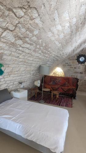 une chambre avec un lit et un mur en pierre dans l'établissement Maison atypique bord de l'Yonne, à Cravant