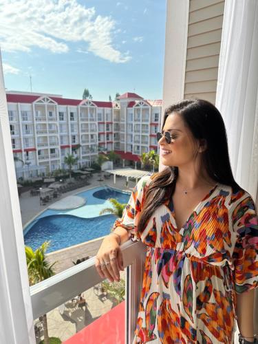 Eine Frau steht auf einem Balkon mit Blick auf den Pool in der Unterkunft São Pedro Thermas Resort Oficial in São Pedro