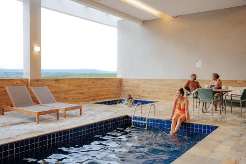 a woman is sitting in a swimming pool at São Pedro Thermas Resort Oficial in São Pedro