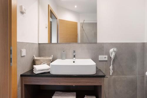 bagno con lavandino bianco e specchio di Bacchushof Apartment Sauvignon a Termeno
