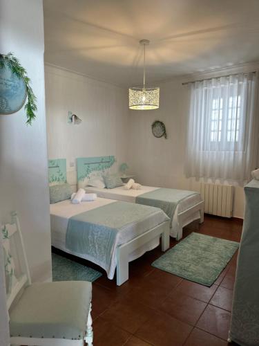 Un dormitorio con dos camas y una lámpara de araña. en Casa do Poço, en Óbidos