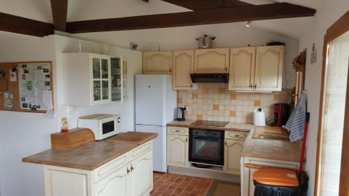 une cuisine avec des armoires blanches et un réfrigérateur blanc dans l'établissement Villa Esperance, à Grand Brassac