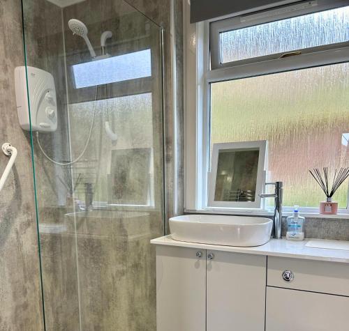 een badkamer met een douche, een wastafel en een raam bij Rum in Oban