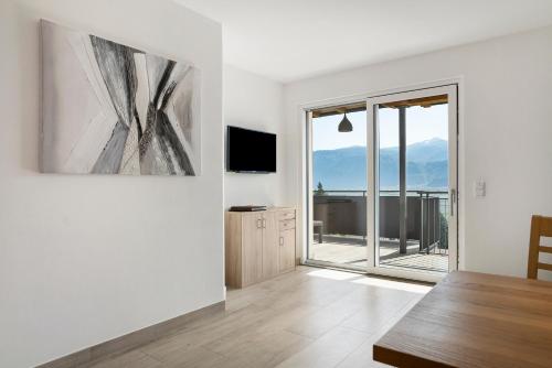 a living room with a television and a large window at Bacchushof Apartment Chardonnay in Termeno