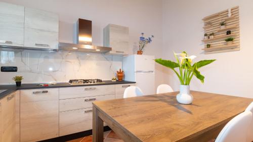 una cucina con tavolo in legno e vaso di fiori di Welcomely - Domo Mea Apartment a Càbras