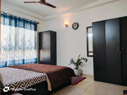 1 dormitorio con 1 cama y reloj en la pared en SOLACE Premium 3BHK Apartment Manyata Tech Park and Mall of Asia en Bangalore