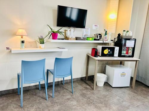 a bar with two blue chairs and a desk with a tv at Hotel Bed & Bike in Cesena