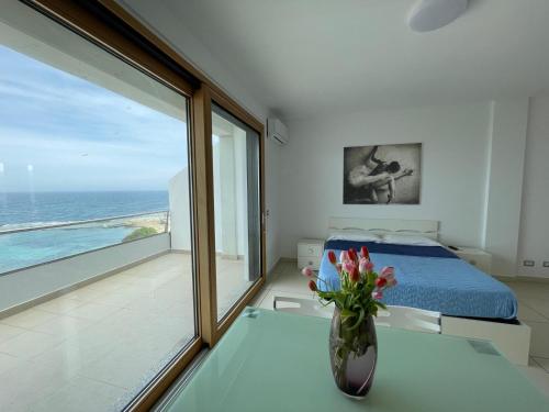 - une chambre avec un lit et un vase avec des fleurs sur une table dans l'établissement Casa Vacanza Acquamarina, à Porto Torres
