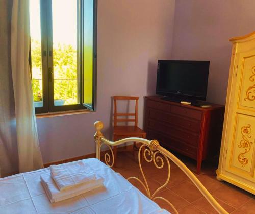 - une chambre avec un lit, une télévision et une commode dans l'établissement Casale Neocastrum, à Lamezia Terme