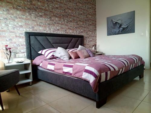 a bedroom with a large bed with a brick wall at New apartment in Tilal Fanar resort pool Tennis in Beit Meri
