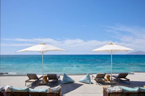 馬斯蒂卡里的住宿－Ammos Luxury Resort，海滩上的一组椅子和遮阳伞