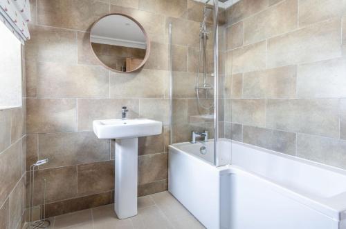a bathroom with a sink and a tub and a mirror at Haven View - 2 Bedroom Apartment - Milford Haven in Milford Haven
