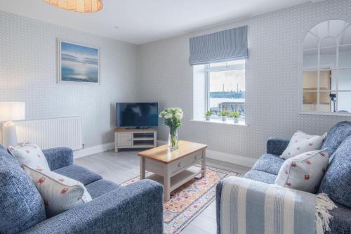 a living room with two blue chairs and a tv at Haven View - 2 Bedroom Apartment - Milford Haven in Milford Haven