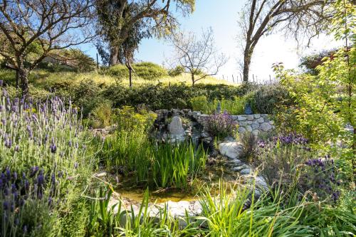 a garden with purple flowers and a stone wall at Serene Vineyard Chateau with Pool, Hot Tub, BBQ in Carmel Valley
