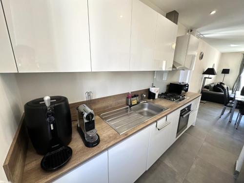 une cuisine avec des armoires blanches et un évier dans l'établissement Appartement vieux village, à Villeneuve-Loubet