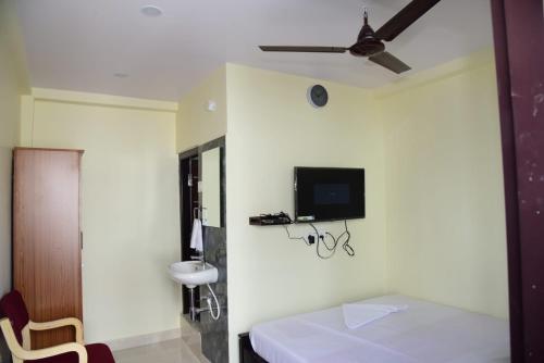 Habitación con cama y TV en la pared. en ARUNA GRAND en Visakhapatnam