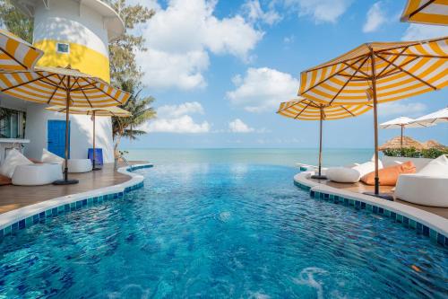 a pool with umbrellas and the ocean in the background at Sea of Love Suite Cafe Pattaya in Bang Sare