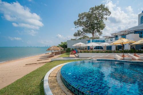 a swimming pool next to a beach with umbrellas at Sea of Love Suite Cafe Pattaya in Bang Sare