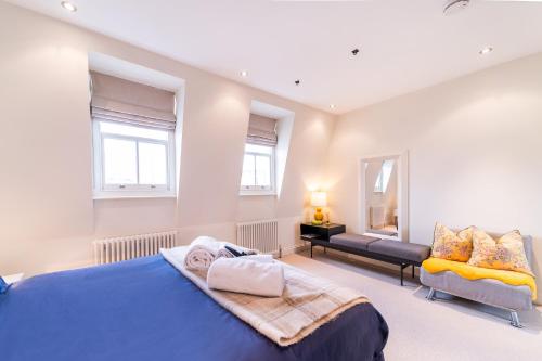 ein Schlafzimmer mit einem blauen Bett und einem Sofa in der Unterkunft Mrs K Stunning 3 bedrooms apartment Chelsea in London