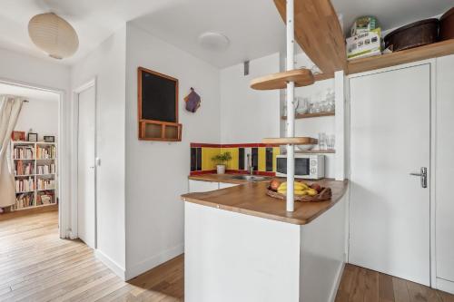 - une cuisine avec des placards blancs et un comptoir avec un bol de fruits dans l'établissement Peace and Quiet appartement at Goutte d'Or by Weekome, à Paris