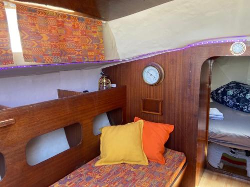Habitación pequeña con cama y reloj en barco en Nuit insolite dans un petit voilier, en La Rochelle