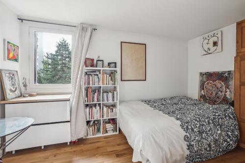 - une chambre avec un lit et une étagère avec des livres dans l'établissement Peace and Quiet appartement at Goutte d'Or by Weekome, à Paris