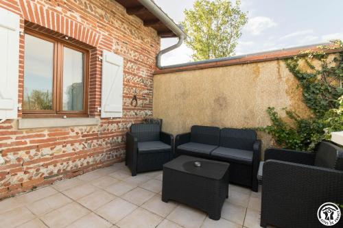 a patio with chairs and a table and a brick wall at Le gîte du Moulin in Lagardelle-sur-Lèze