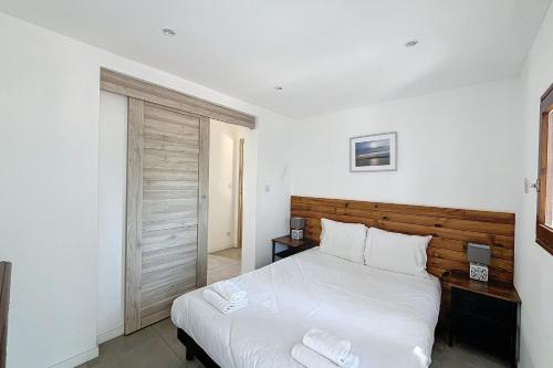 - une chambre avec un grand lit blanc et une tête de lit en bois dans l'établissement Mini Villa At 150m From The Beach Of Santa Giulia, à Porto-Vecchio