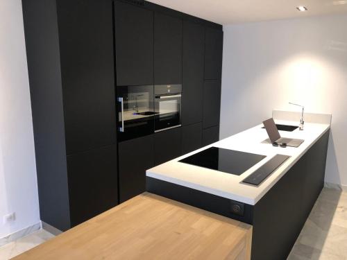 une cuisine avec des armoires noires et un comptoir blanc dans l'établissement center of cannes, à Cannes