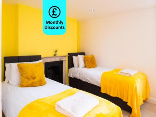 - 2 lits dans une chambre aux murs jaunes dans l'établissement Large Apartment - Eleven Charlotte House x 2 Bathrooms, à Ipswich