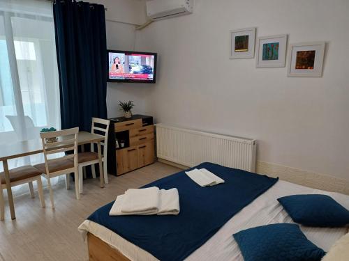 een slaapkamer met een bed, een tafel en een televisie bij Lora Studio in Mamaia Nord – Năvodari