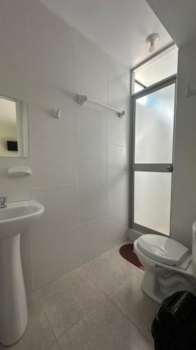 a white bathroom with a toilet and a sink at La Herencia - Oxapampa in Oxapampa