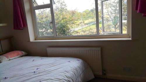 a bedroom with a bed and a large window at Exceptional Rated 10, 15 mins from East Croydon to Central London, Gatwick - Spacious, Sleeps up to 16 plus Cot - Free WiFi, Parking - Next to Lloyd Park, Great for Walkers - Ideal for Contractors - Families - Relocators in Croydon