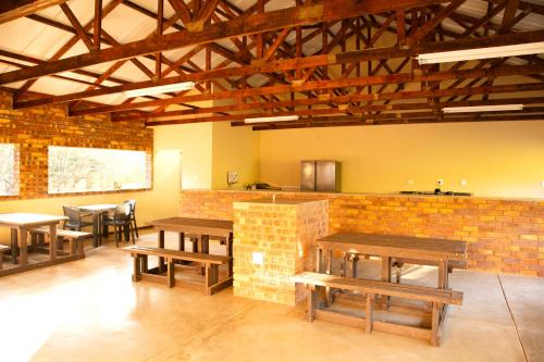a restaurant with wooden tables and a brick wall at Melamar Estate in Marloth Park